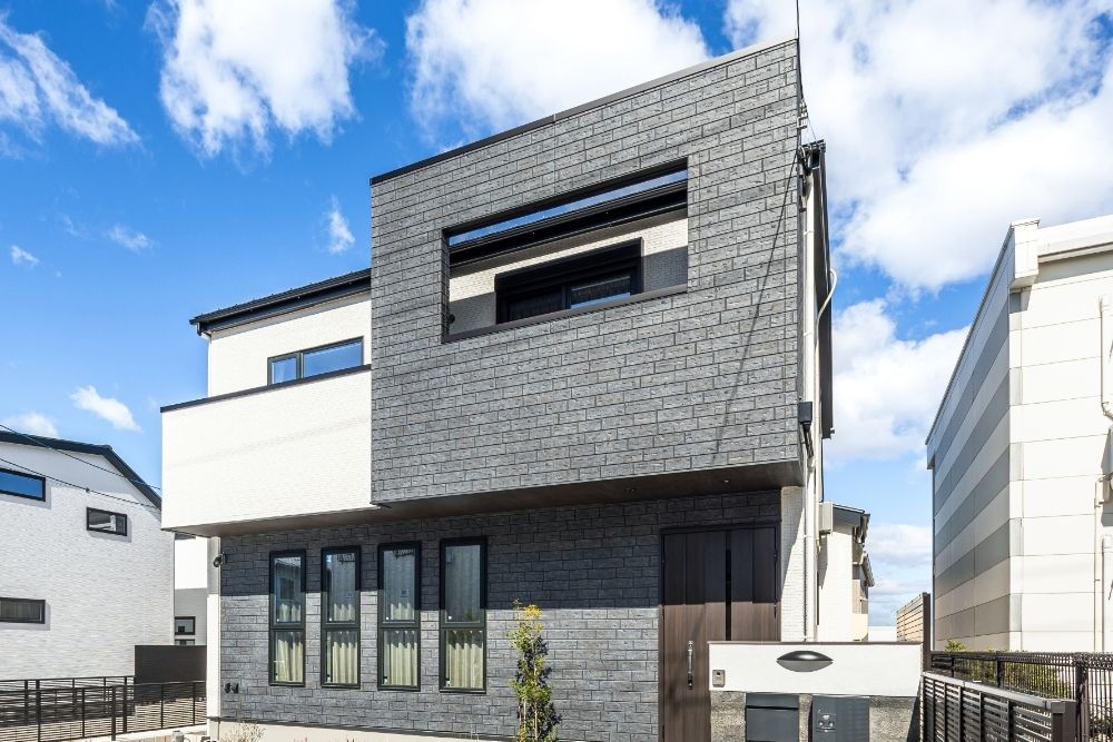 青空に映える玉善のモダンな注文住宅の外観。黒と白のコントラストが美しいデザインと、プライバシーに配慮した窓配置。